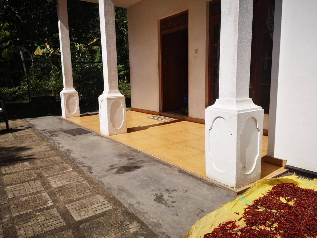 een kamer met 3 zuilen en een houten vloer bij Sithu Guesthouse in Bentota