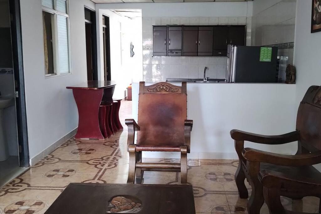 a living room with chairs and a kitchen with a counter at Hermosa casa familiar in La Tebaida