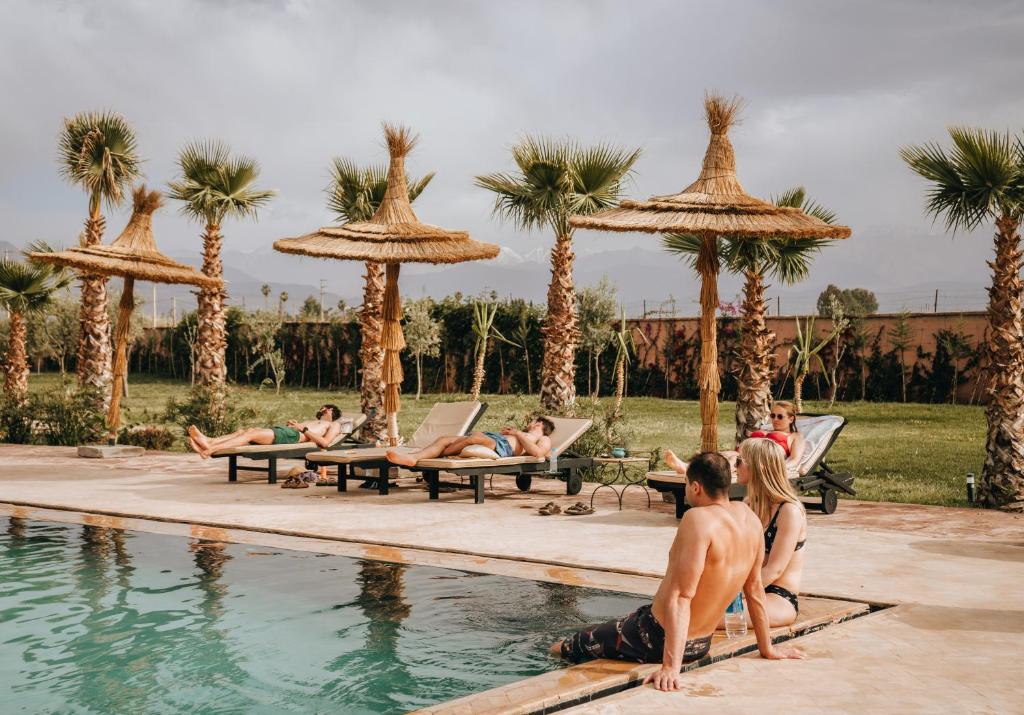 um grupo de pessoas sentadas ao redor de uma piscina em Aghmat Lodge Guest house em Marrakech