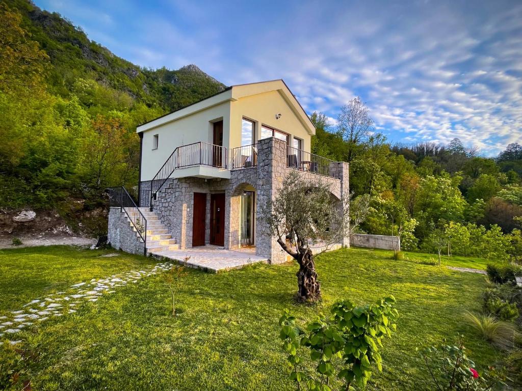 a house on a hill with a tree in the yard at Prevalis Nature Cottage in Virpazar