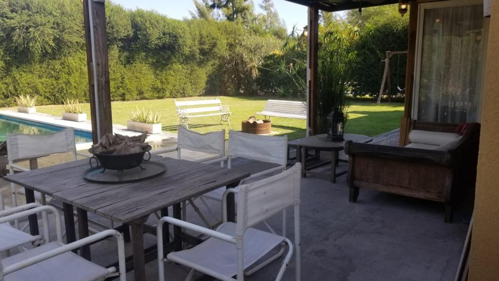 un patio con mesa, sillas y piscina en Hermosa casa con fogonero, parrilla cubierta, pileta y jardin parquizado en Benavídez