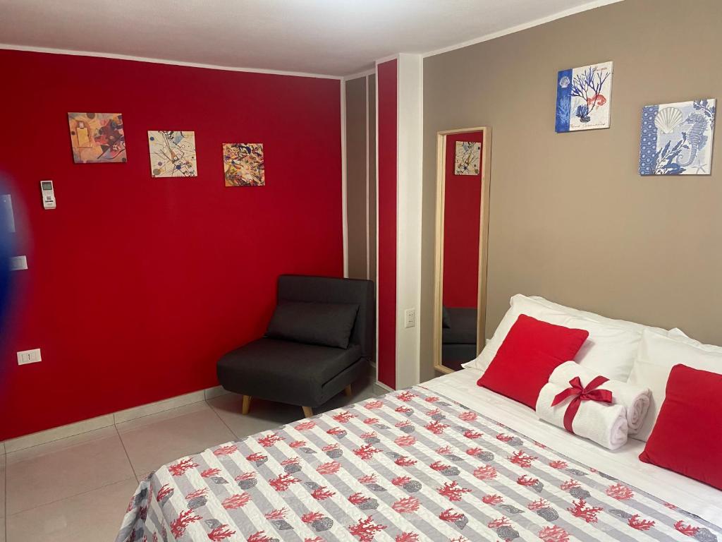 una camera da letto con una parete rossa, un letto e una sedia di LAGUNA BLU Camera TRAMONTO con terrazza panoramica in comune a Chioggia