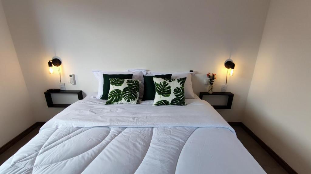 sypialnia z białym łóżkiem z zielonymi poduszkami w obiekcie Villa da Serra w mieście Alto Paraíso de Goiás
