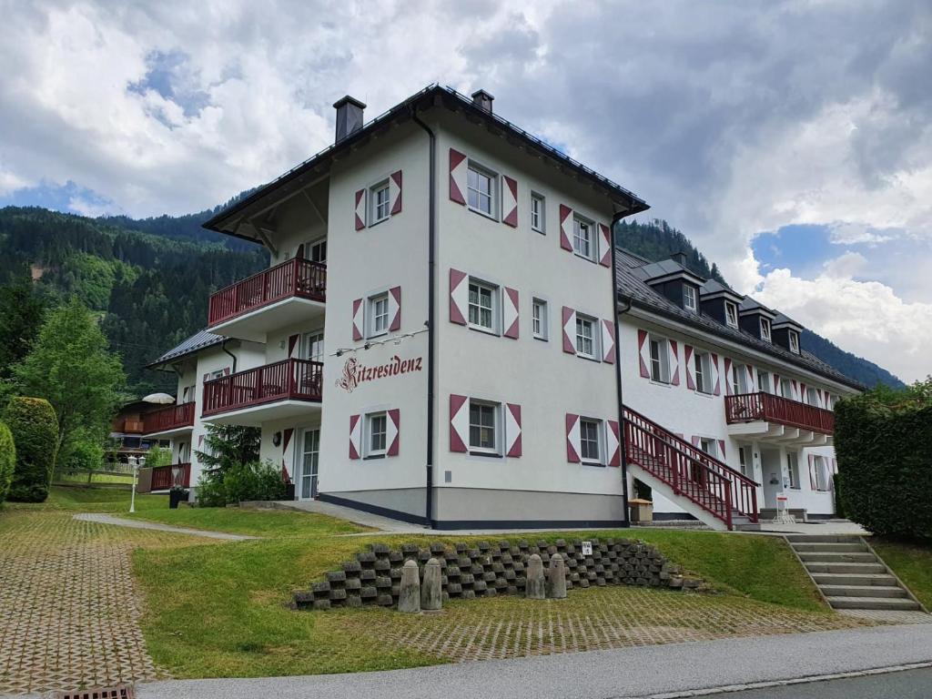 a large white building with red shuttered windows at Kitz Residenz Eleven by All in One Apartments in Kaprun