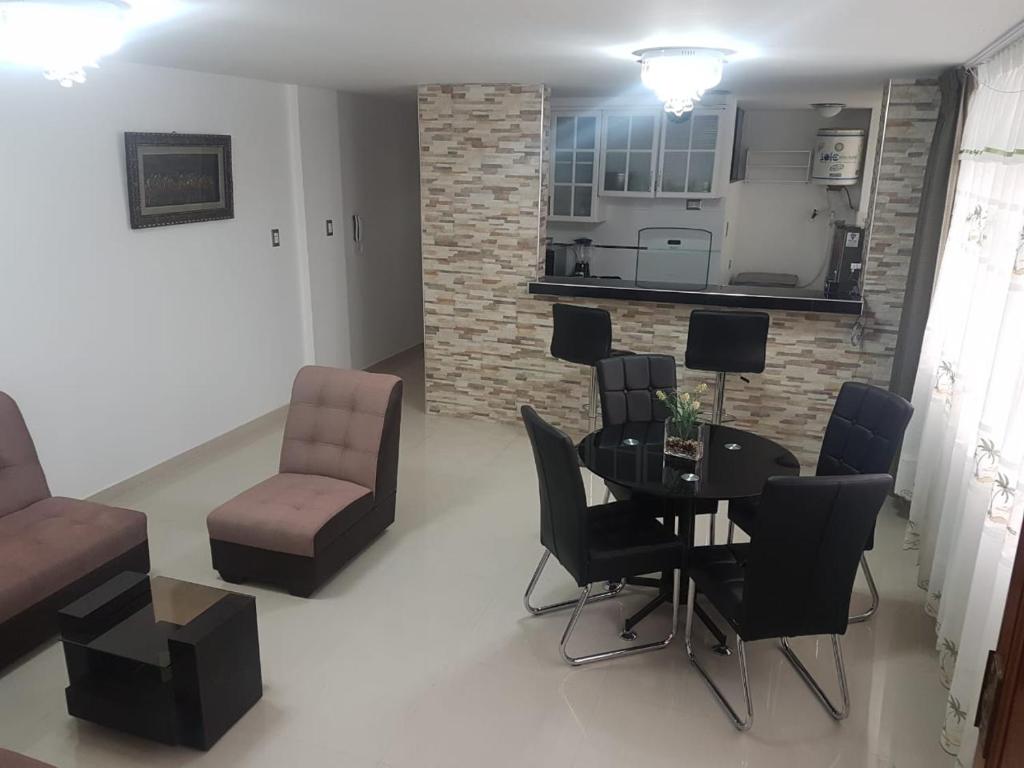 a living room with a table and chairs and a kitchen at Queen's Residence VIP in Tacna