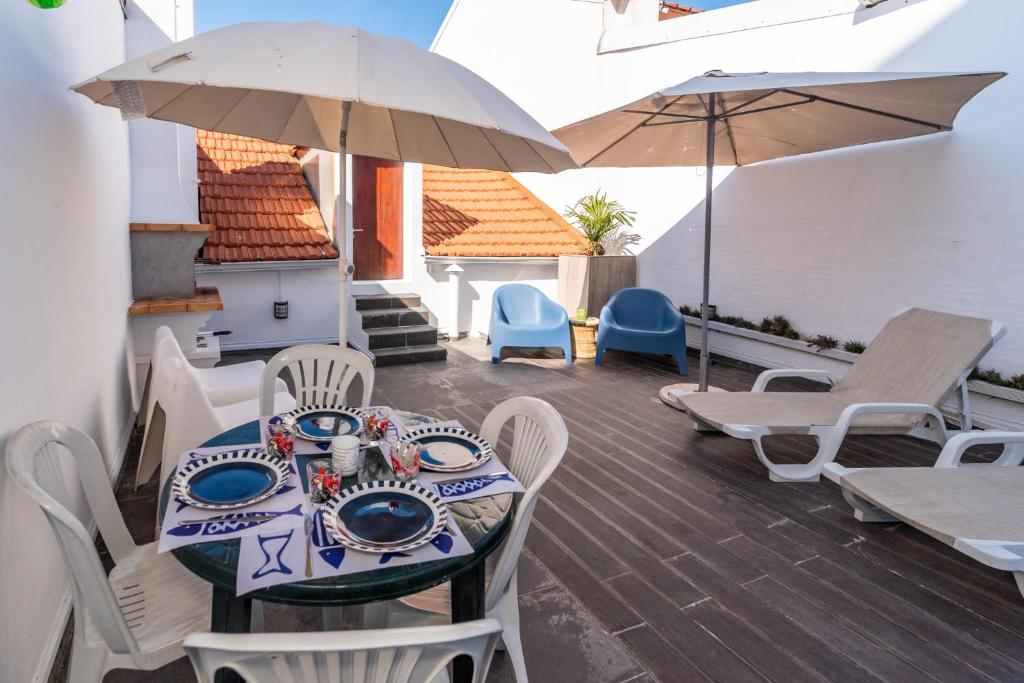 a patio with a table and chairs and umbrellas at Beach House City in Figueira da Foz