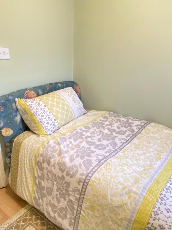 a bed with a comforter and pillows in a bedroom at Your Cosy and Welcoming HomeStay!! in Ilford