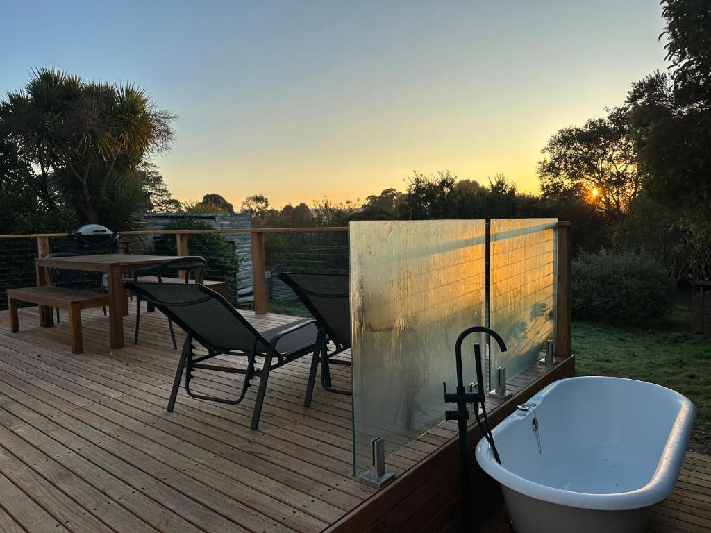 une terrasse en bois avec une baignoire et une table dans l'établissement Enjoy a renovated retreat with outdoor bath, à Creswick