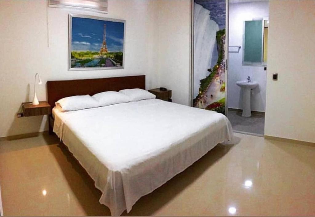 a bedroom with a large white bed in a room at Hotel Suites Caribe in Barranquilla