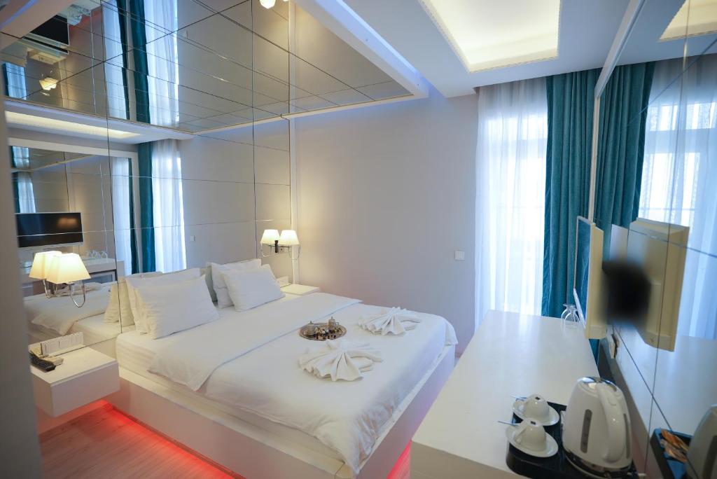 a bedroom with a white bed and a television at Sea Front Pansiyon in Antalya