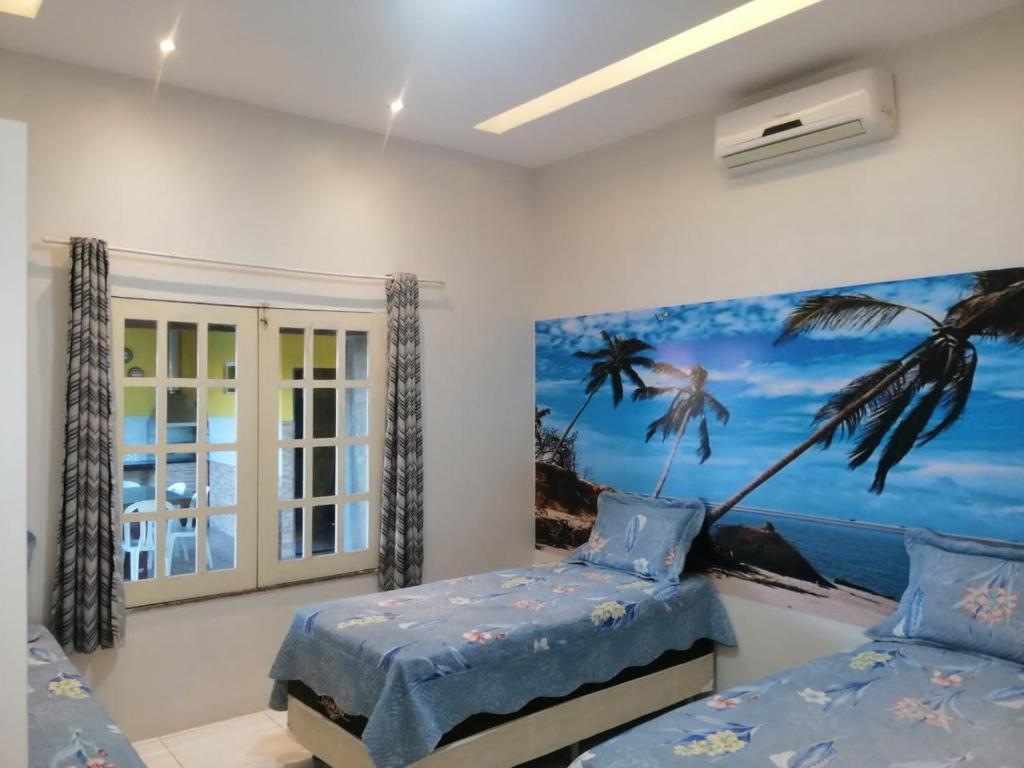 a bedroom with two beds and a painting of a palm tree at CASA TEMPORADA Barreirinhas in Barreirinhas