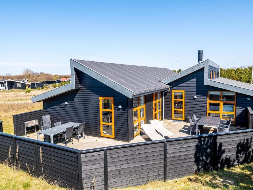ファーンにある6 person holiday home in Fanøの黄色い窓とパティオのある青い家