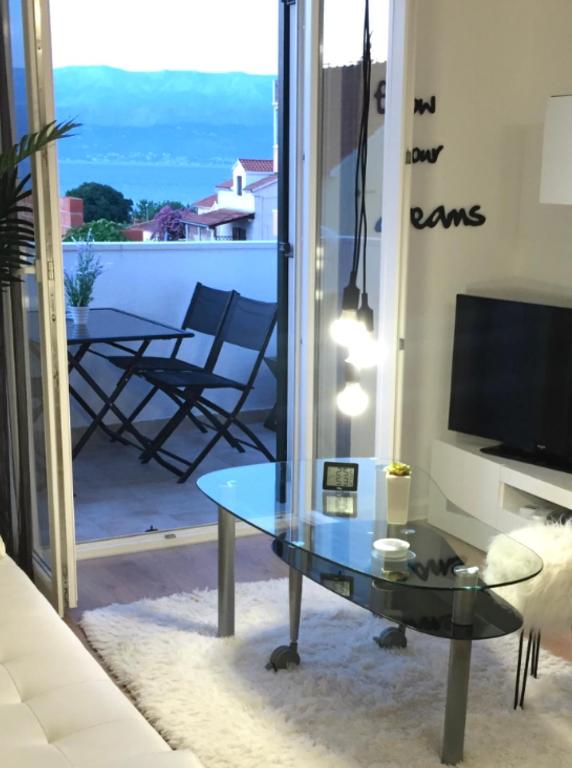 a living room with a glass table and a television at Apartment New Chic in Supetar