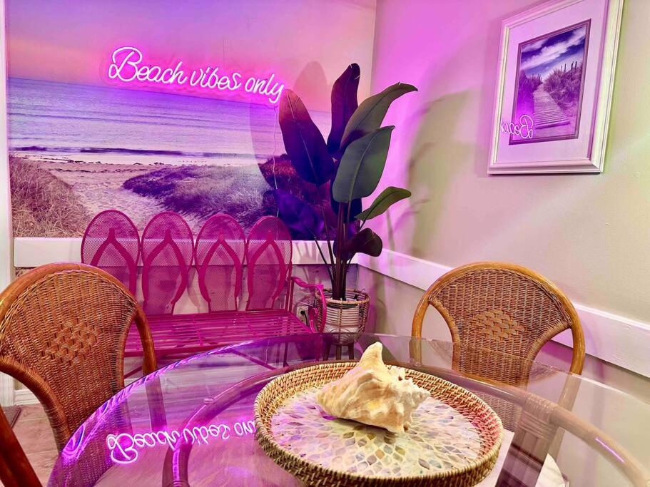 une table avec des chaises et un panneau violet sur le mur dans l'établissement Sandcastles and Sunshine - Gulf Highlands Beach Resort, à Panama City Beach