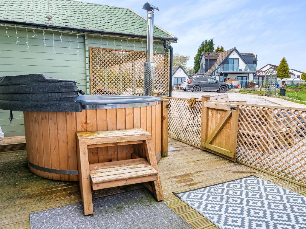 a wooden deck with a hot tub and a fence at Pendle View Lodge in Altham