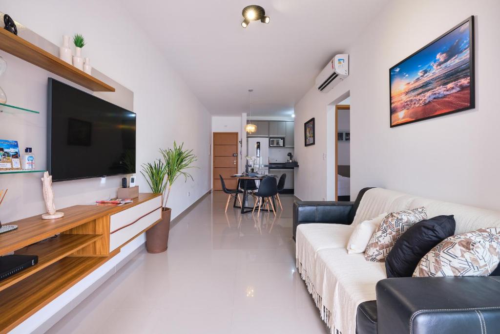 uma sala de estar com um sofá e uma televisão de ecrã plano em 2 QUARTOS com Churrasqueira na Varanda, Piscina, Garagem interna, WiFi 500mbps, Ar Condicionado e Telas de Proteção em Ubatuba