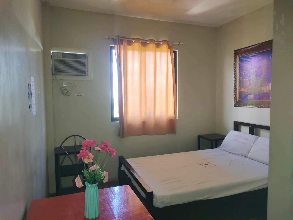 Habitación pequeña con cama y mesa con flores en WJV INN CASUNTINGAN, en Mandaue