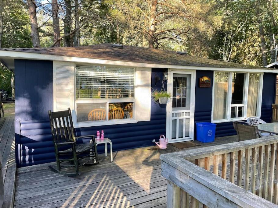 ein blaues Haus mit einem Schaukelstuhl auf einer Terrasse in der Unterkunft The “Bear” waterfront cabin in Muskoka in Utterson