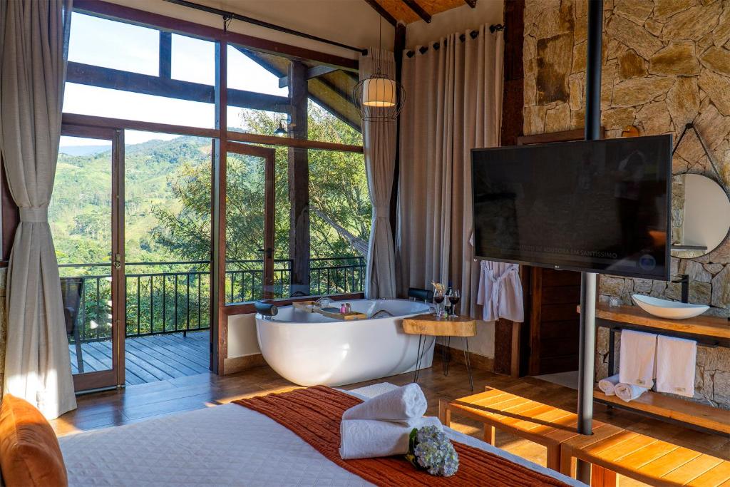 a bathroom with a tub and a tv and a television at Monte Mauá Chalés in Visconde De Maua