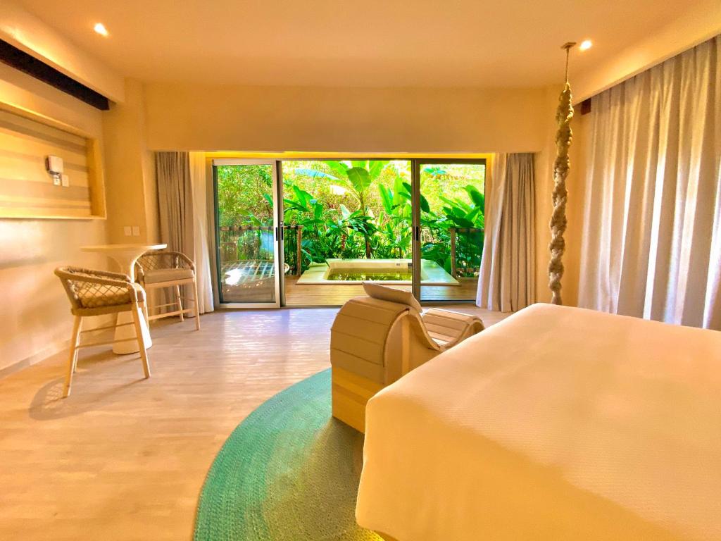 a bedroom with a bed and a couch and a table at Hotel Shibari - Restaurant & Cenote Club in Tulum