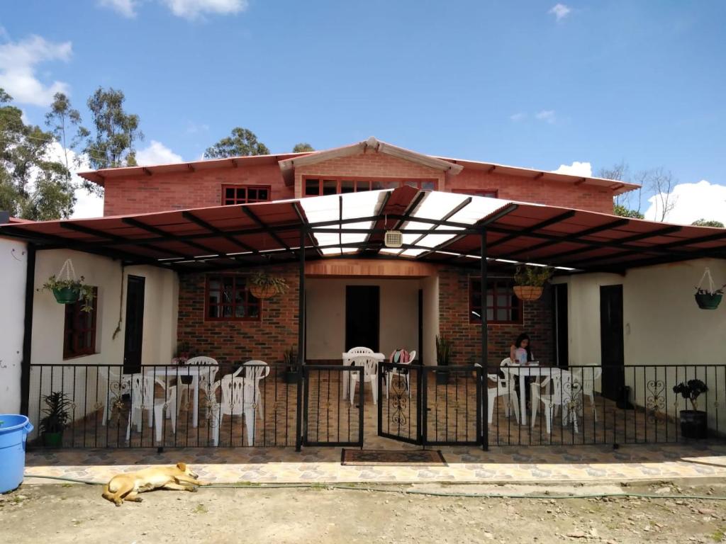 a house with a dog laying in front of it at Hostal Agroturistico Guadalupe in Saboyá