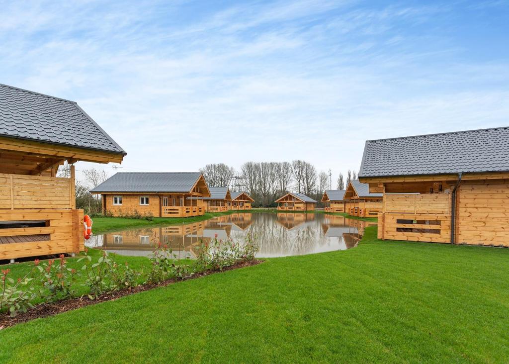 a row of wooden homes with a pond in the yard at Holly Tree Lodges in York