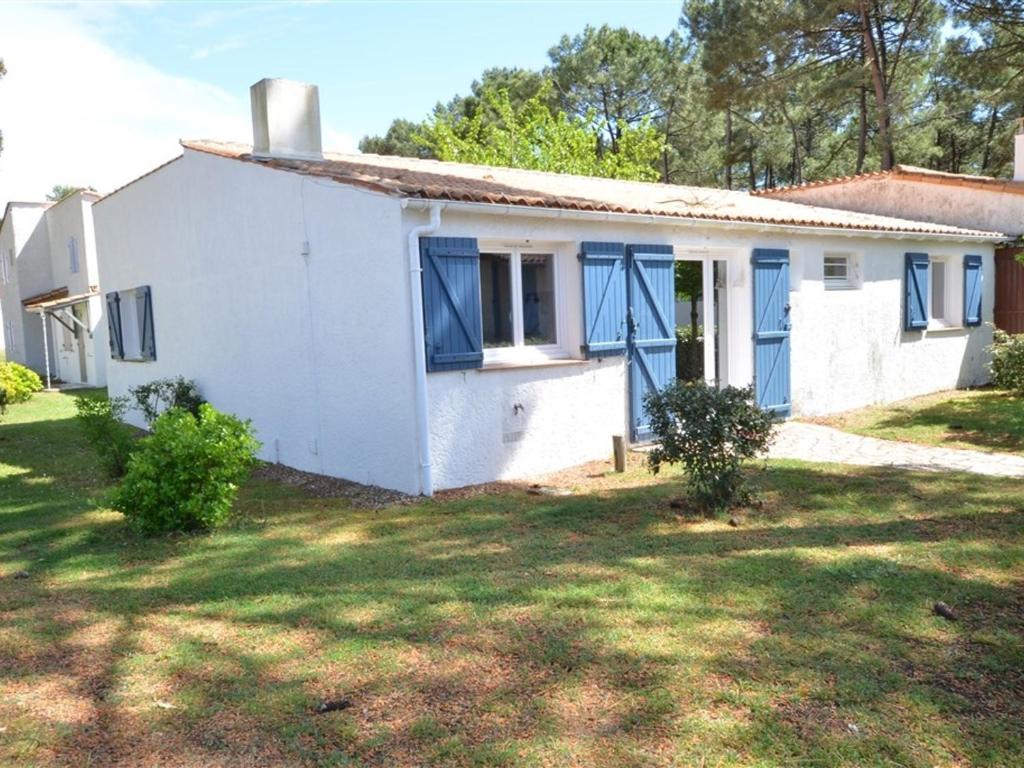 une maison blanche avec des fenêtres bleues et une cour dans l'établissement Maison 4 pièces près mer et port La Palmyre - 7 pers., WiFi, animaux OK, parking, patio, ménage inclus - FR-1-705-36, aux Mathes