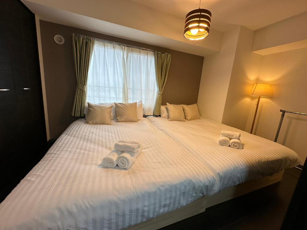 札幌市にあるSun Court Hongo dohri Garden Hillsのベッドルーム1室(ベッド1台、タオル2枚付)
