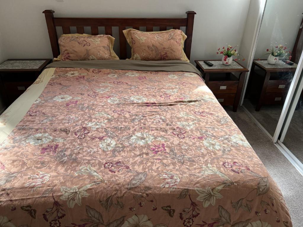 a bedroom with a bed with a floral bedspread at Guest Suite - Cosy place in the Wattle Downs in Auckland