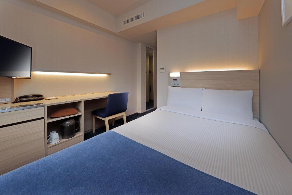 a hotel room with a large bed and a desk at Keio Presso Inn Gotanda in Tokyo