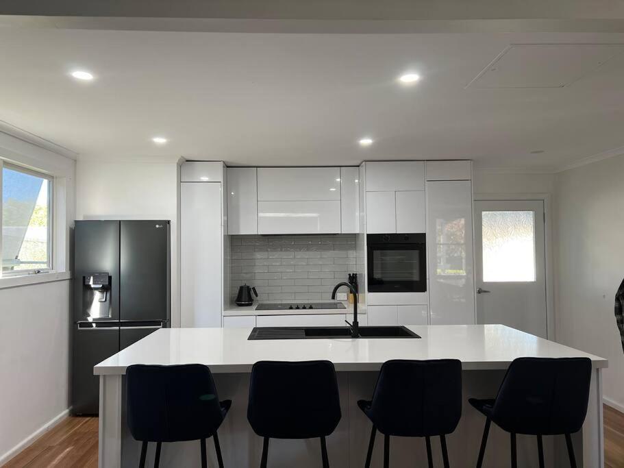 uma cozinha com um balcão branco e electrodomésticos pretos em Cosy Eildon Getaway em Eildon