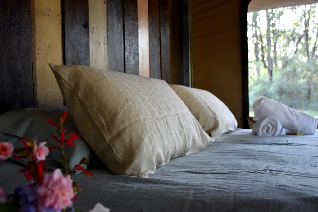 a bed with pillows and flowers on it with a window at On Bell Glamping in Belford