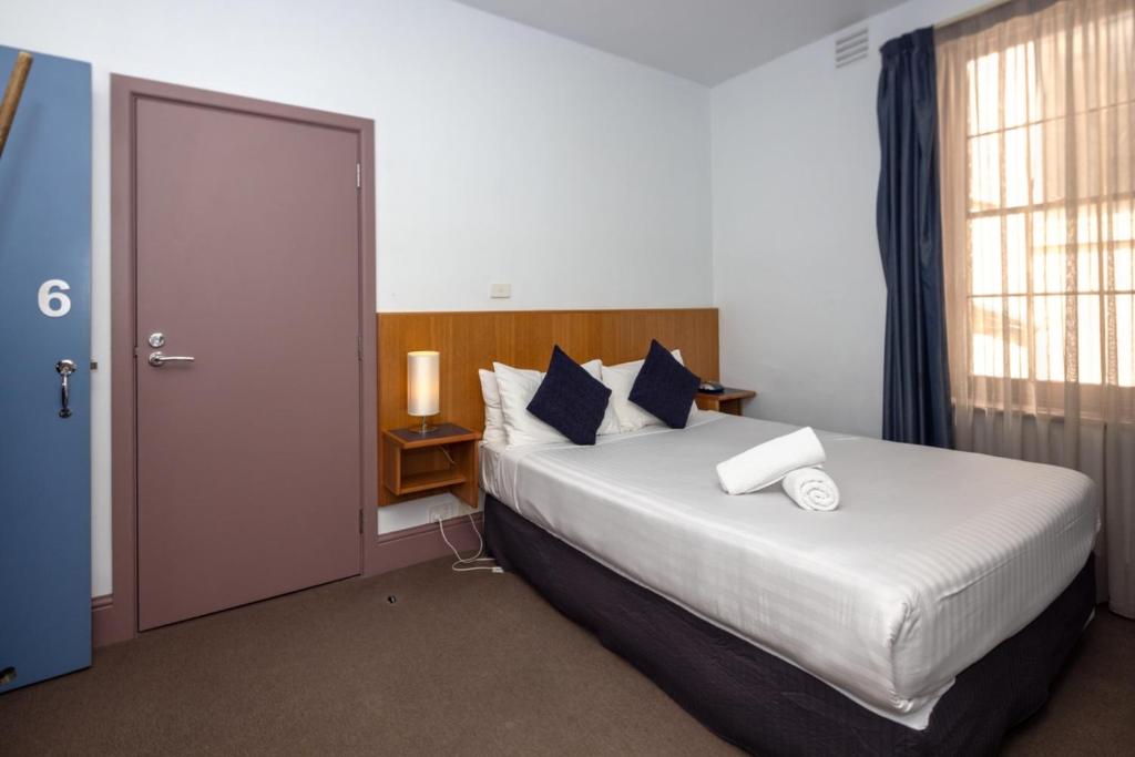 um quarto com uma cama grande e uma janela em Central Hotel Hobart em Hobart