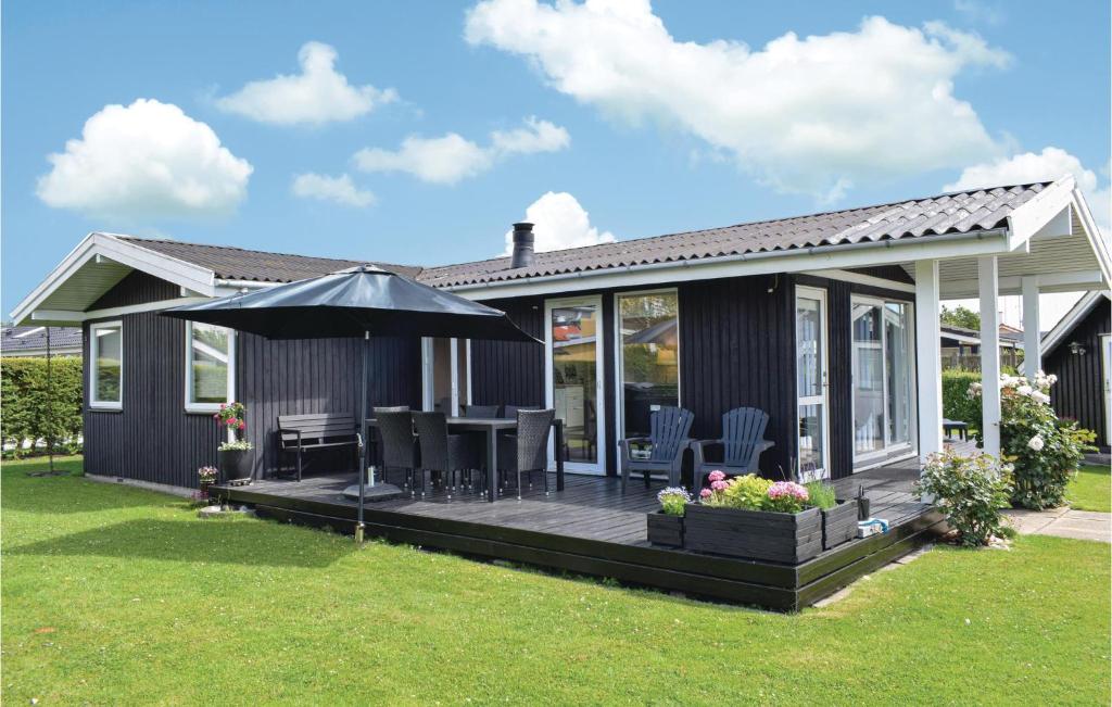 een huis met een terras en een paraplu bij Cozy Home In Brkop With Kitchen in Børkop