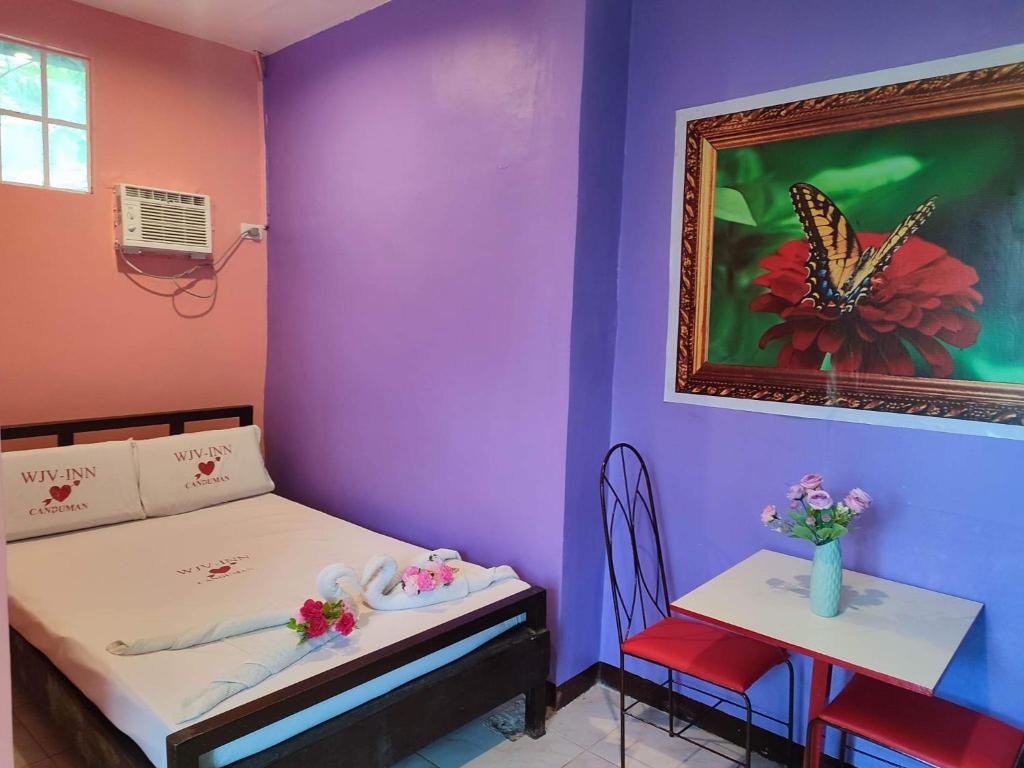 una habitación con una cama y una mesa con una pintura de mariposa en WJV INN CANDUMAN, en Mandaue