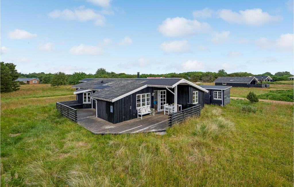 una casa negra con terraza en un campo en Nice Home In Fan With Wifi, en Fanø