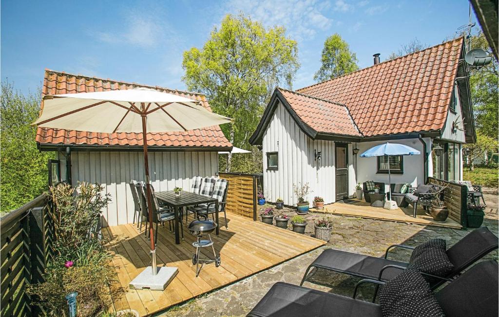 a small house with a wooden deck with an umbrella at Holiday Home Vestre Strandvej Nexø Iii in Balke