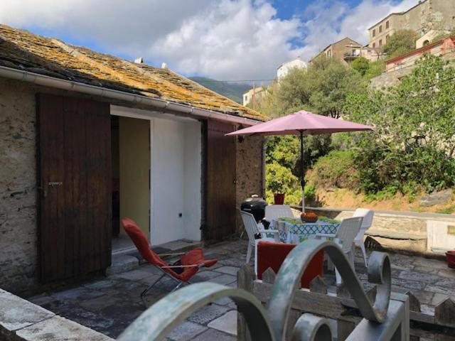 un patio avec une table, des chaises et un parasol dans l'établissement Chez Aurele, à Santa-Maria-di-Lota