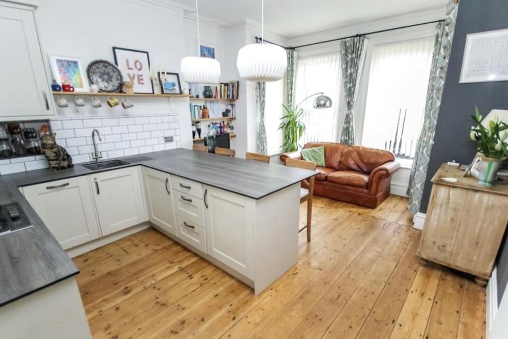 a kitchen with white cabinets and a wooden floor at Lovely Westbourne apartment - 15 min walk to beach in Bournemouth