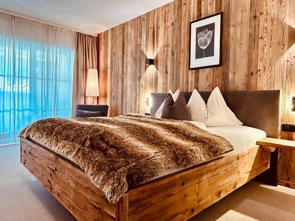 - une chambre avec un grand lit et un mur en bois dans l'établissement Sonn-Alm Chalet-Apartments, à Bichlbach