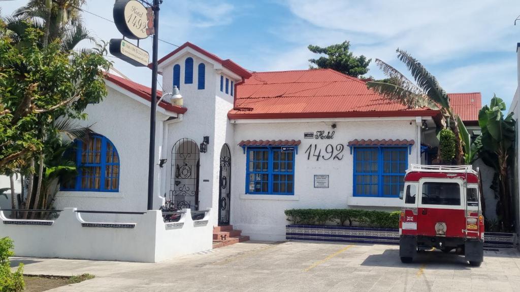 un camión rojo estacionado frente a un edificio blanco en Hotel 1492, en San José