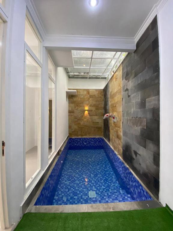 una gran piscina cubierta en una habitación con azulejos azules en Villa Permata Panderman 20 en Batu
