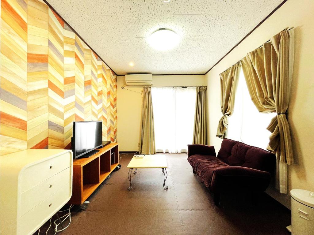 a living room with a couch and a tv at Estate F 201 in Kamatachō