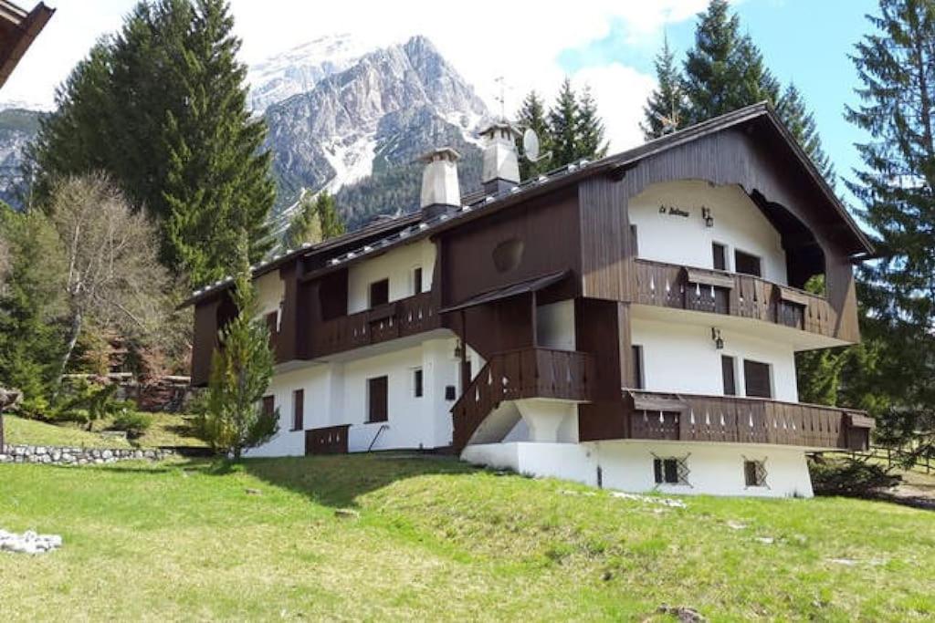 um edifício numa colina com montanhas ao fundo em Appartamento a San Vito di Cadore em San Vito di Cadore