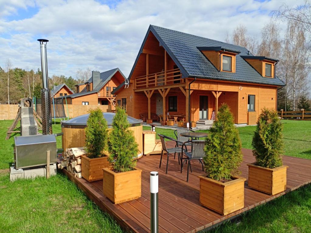 eine Holzterrasse mit einem Tisch und einem Haus in der Unterkunft Chillout House Serwy in Serwy