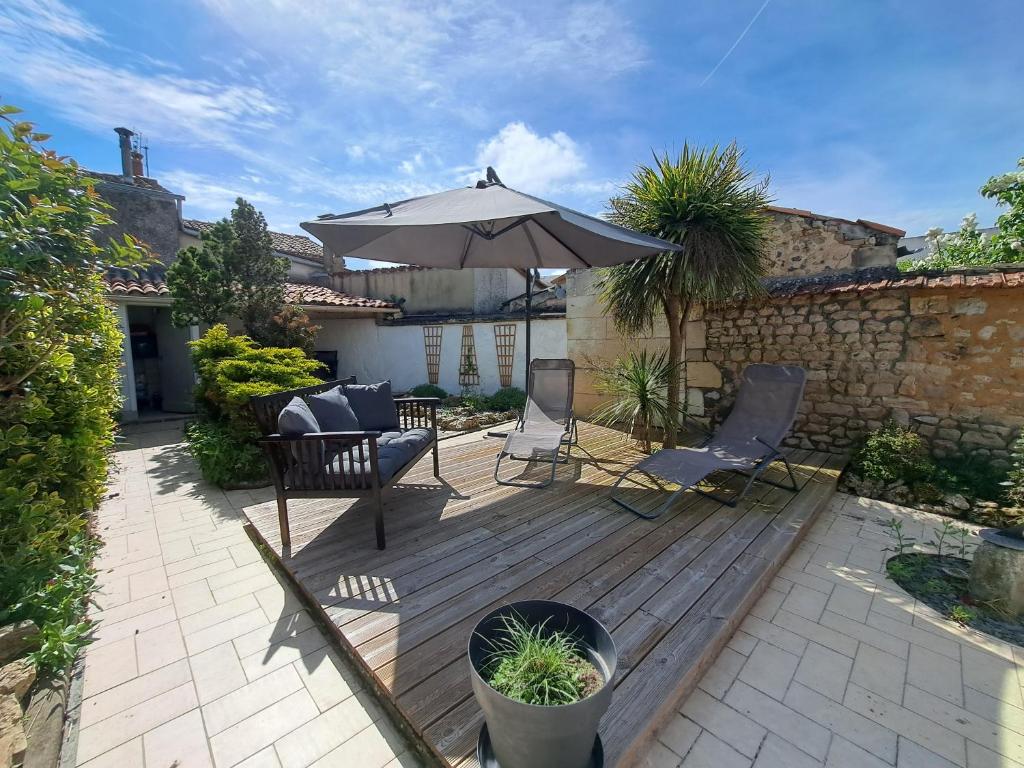 - une terrasse en bois avec un parasol et des chaises dans l'établissement Villa des Thermes, St Jean d'Angély, à Saint-Jean-dʼAngély