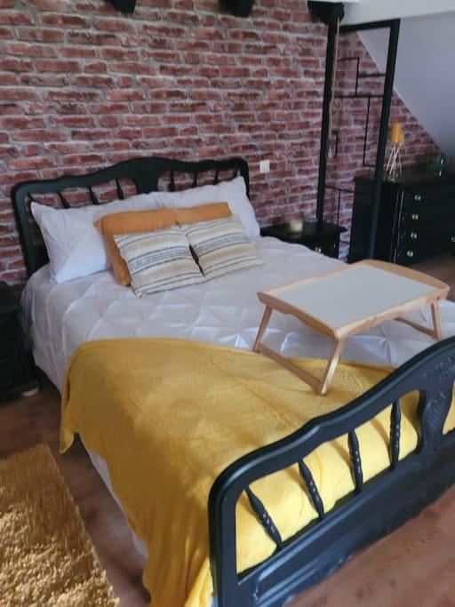 - un lit avec une couverture jaune et une table dans l'établissement petite maison cosy en duplex, à Éguelshardt
