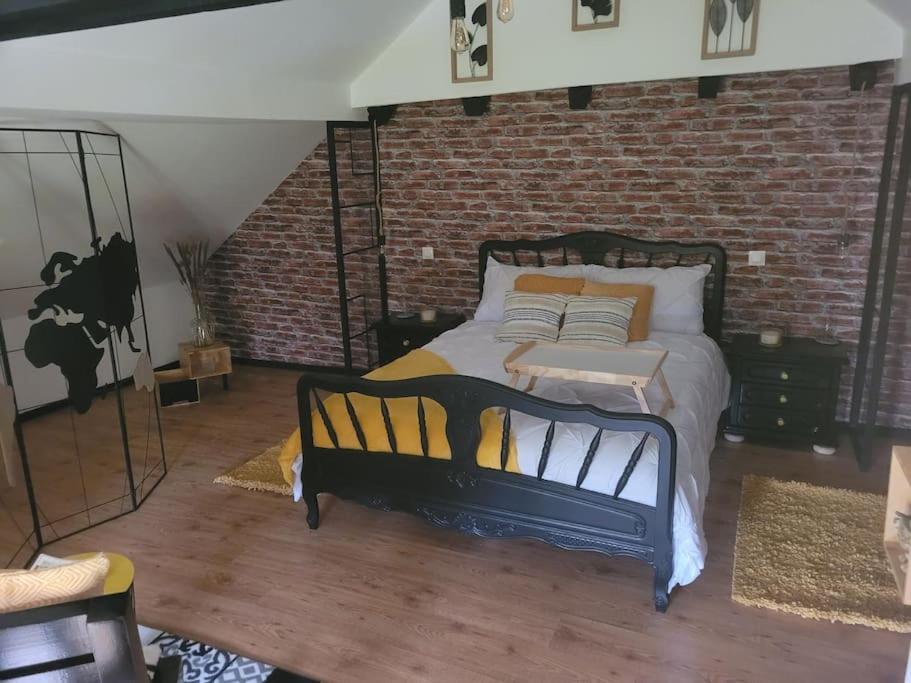 1 dormitorio con cama y pared de ladrillo en petite maison cosy en duplex, en Éguelshardt