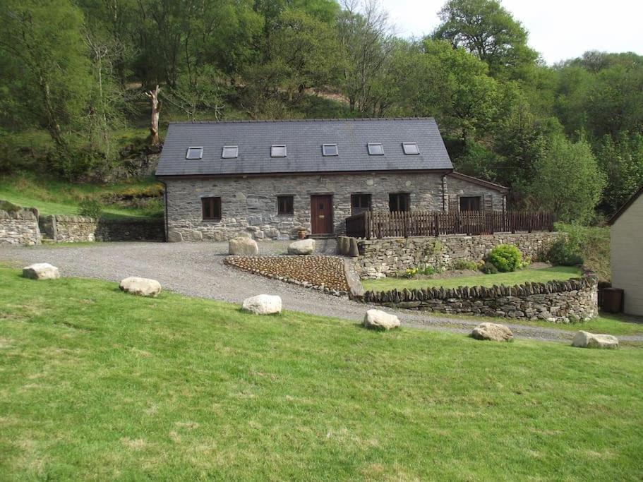 una casa de piedra en un campo con ovejas delante en Cae Coryn Cottages, Snowdonia ( Troed y Graig ) en Bala