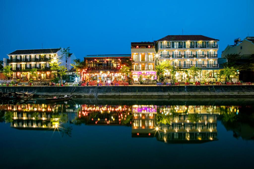a group of buildings next to a river at night at Hoi An Riverland Villa - Hoi An Center in Hoi An